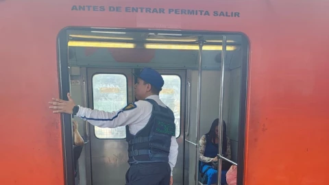 Vagón del metro con puerta abierta y un policía en la entrada.