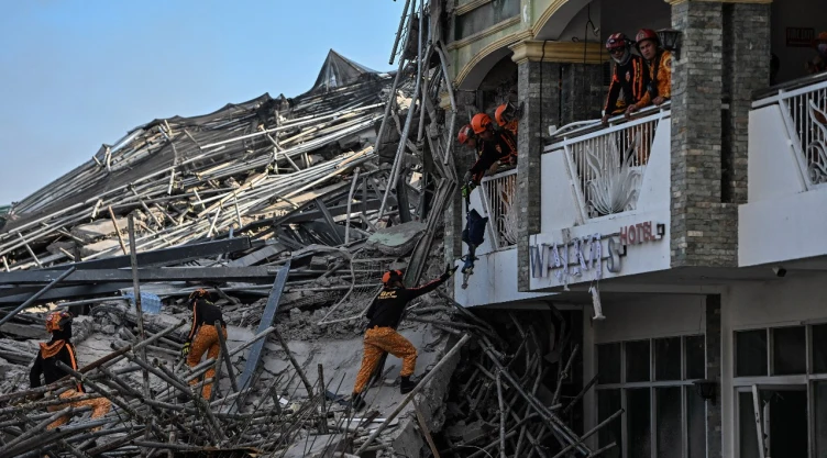 Un rescatista pasa equipo a un compañero entre los escombros tras el derrumbe de un edificio de nueve pisos en construcción en Balibago, Ciudad de Ángeles, Pampanga, Filipinas , el 24 de mayo de 2026.