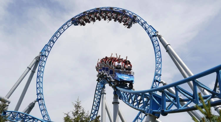 Montaña Rusa en acción en el parque temático, con todos los pasajeros a bordo, unos en plena bajada y otros cabeza hacia abajo