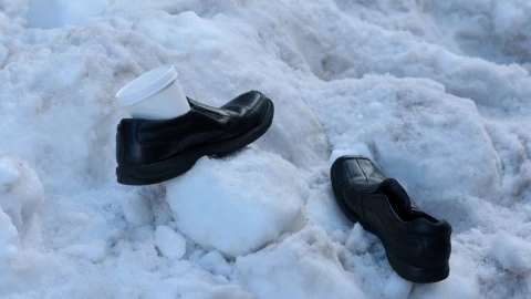 Un hombre deja sus zapatos de trabajo y un recipiente de sopa en una pila de nieve mientras espera su autobús, mientras la gente sigue lidiando con las consecuencias de una gran tormenta invernal que arrojó nieve y hielo en una gran franja de los Estados Unidos, en Washington, DC, EE. UU., el 27 de enero de 2026.