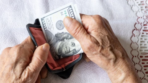 Una mujer mete los dólares en su billetera.