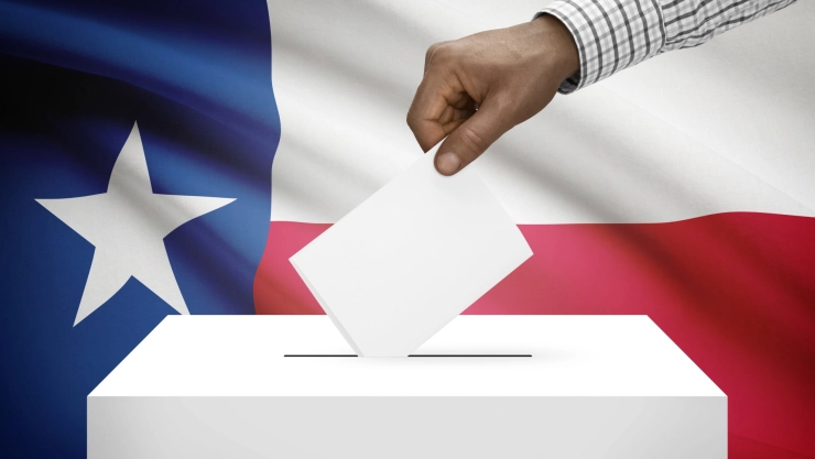Ciudadano estadounidense deja su voto en la urna con la bandera de Texas en el fondo