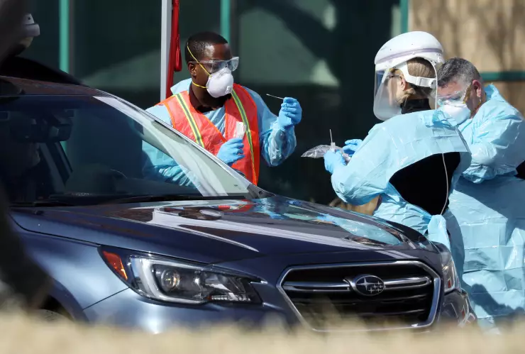 Health care workers test people at a drive-thru testing station run by the state health department, for people who suspect they have novel coronavirus, in Denver, Colorado