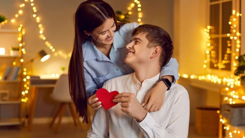 Una pareja sostiene un corazón rojo.