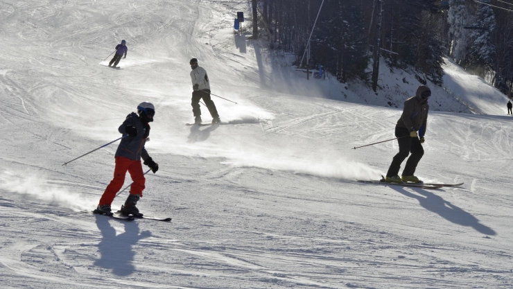 unos jóvenes se deslizan por una montaña cubierta de nieve.