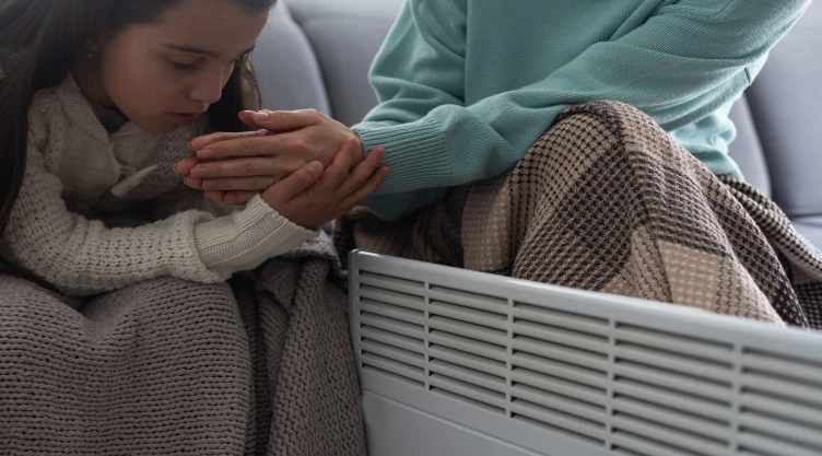 una niña y su madre se refugian del frío con la calefacción