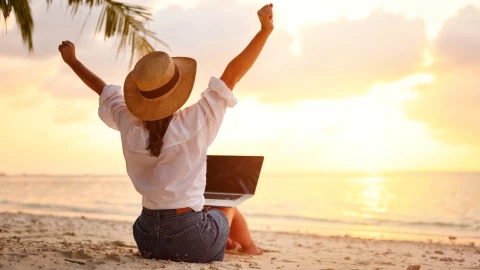 Mujer de espaldas levanta sus brazos en la playa