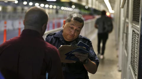 En esta fotografía del 17 de septiembre de 2019, un agente del Servicio de Aduanas y Protección Fronteriza, verifica los documentos de migrantes que pretenden solicitar asilo en Estados Unidos, en el Puente Internacional 1 después de que llegaron
