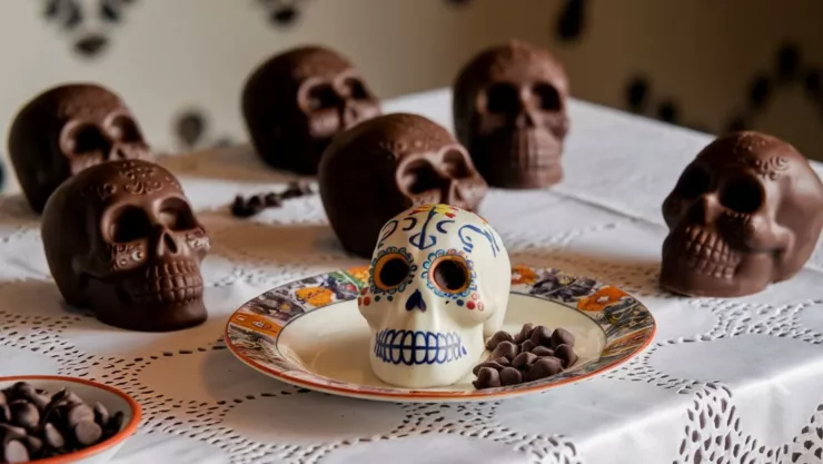Una foto de una mesa con un mantel blanco. Hay varias calaveritas de chocolate sobre la mesa.