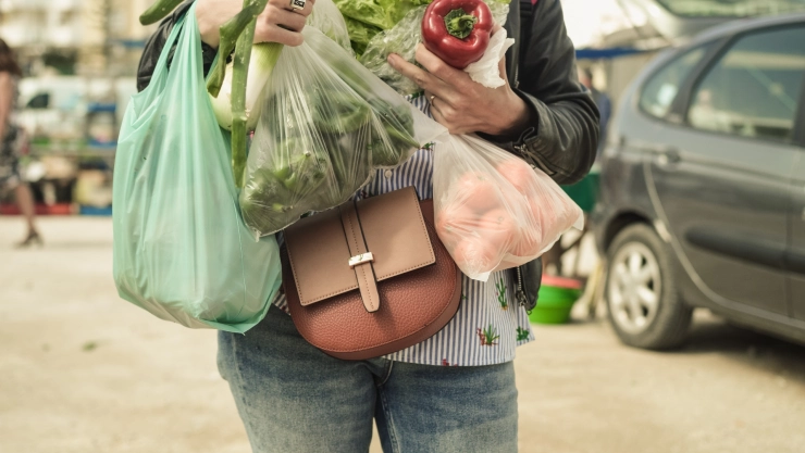 Una mujer con bolsas de plástico saliendo de un supermercado