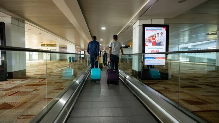 Dos personas recorren el pasillo de un aeropuerto.