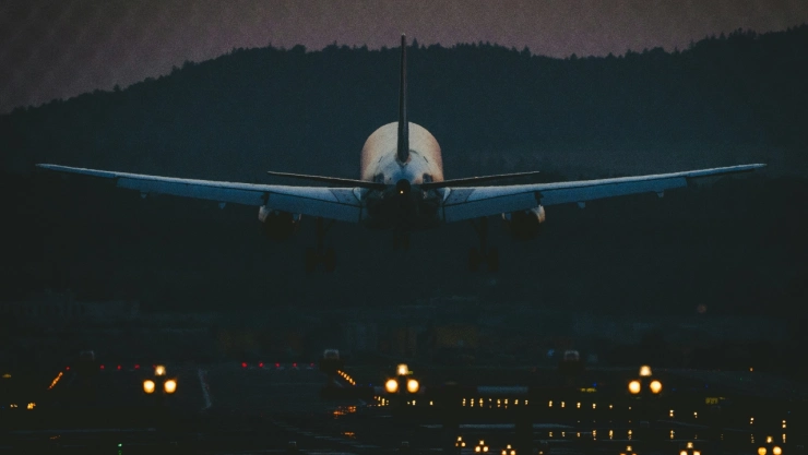 Avión aterrizando en aeropuerto en cielo nocturno.