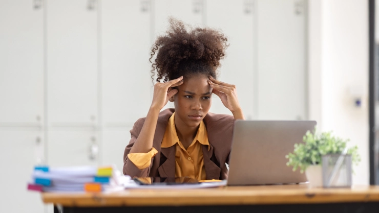 Una mujer se agarra la cabeza frente a una computadora