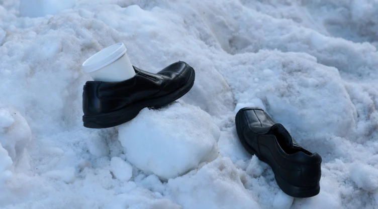 Un hombre deja sus zapatos de trabajo y un recipiente de sopa en una pila de nieve mientras espera su autobús, mientras la gente sigue lidiando con las consecuencias de una gran tormenta invernal que arrojó nieve y hielo en una gran franja de los Estados Unidos, en Washington, DC, EE. UU., el 27 de enero de 2026.