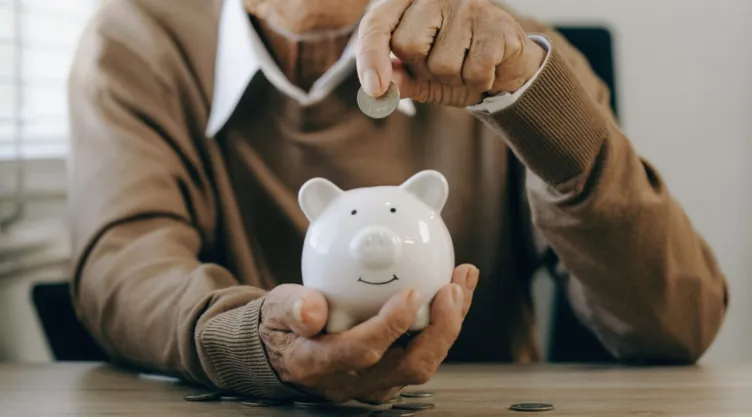 Una persona pone unas monedas en una alcancía.