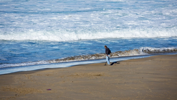Un hombre limpia basura cerca del mar