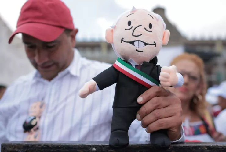 hombre en el Zócalo de la CDMX sujetando un peluche de AMLO