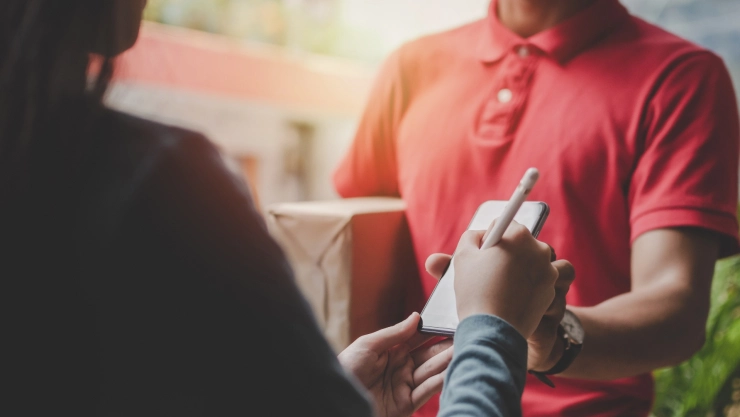 un repartidor entrega un paquete a una mujer.