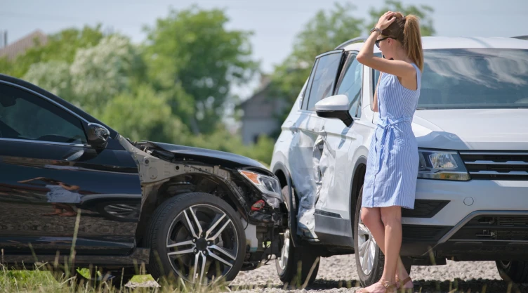Una mujer junto a dos coches que chocaron.