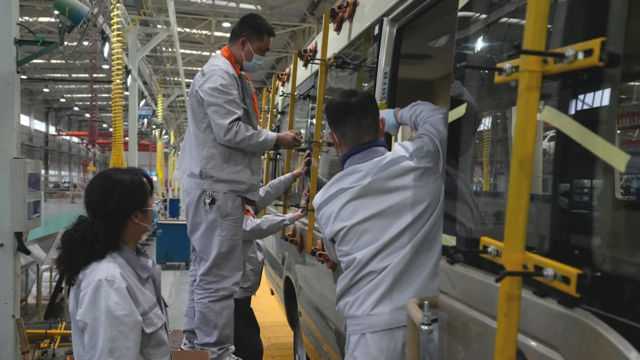 Trabajadores chinos instalan cristales a un minibús.