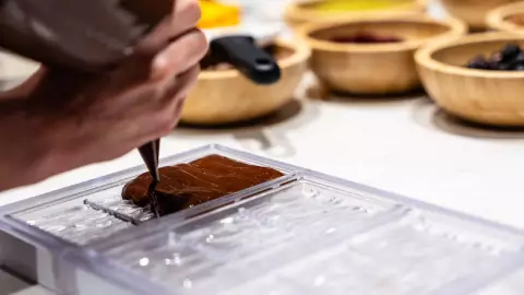 un chef vierte el chocolate de una manera muy cuidadosa
