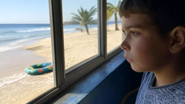 (Imagen generada con IA) Un niño mira triste a la playa desde su casa porque recorrieron las vacaciones de Semana Santa 2025 en México.