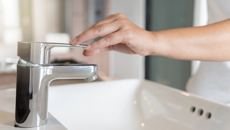 Una personas cierra el grifo de agua.