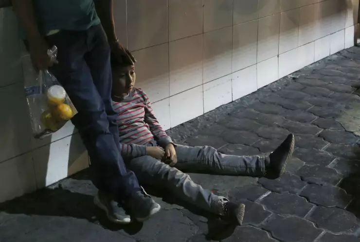 En esta imagen, tomada el 18 de julio de 2019, un niño migrante y su padre esperan junto luego de que las autoridades migratorias mexicanas los trasladaron en autobús desde Nuevo Laredo. Imagen, AP.