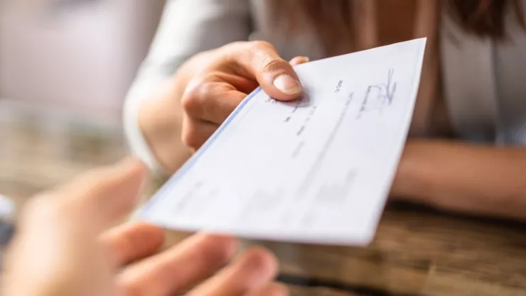 Una persona entrega un cheque a otra,