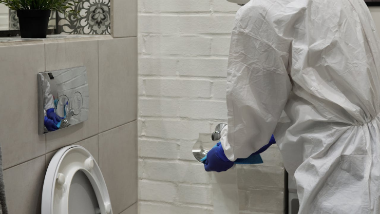Hombre con traje especial limpiando el WC