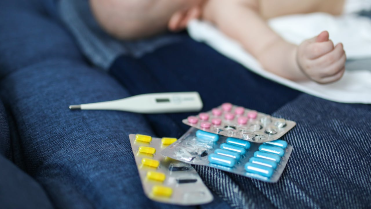 Un menor de edad a lado de pastillas y un termómetro.