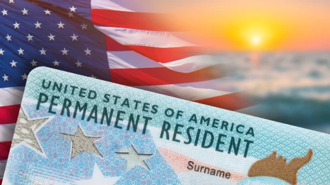 Una tarjeta de residencia permanente sobre una bandera de Estados Unidos.