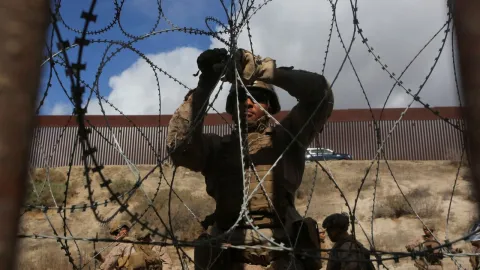 Un infante de marina estadounidense ajusta un alambre de concertina a lo largo de la valla principal en la frontera entre México y Estados.