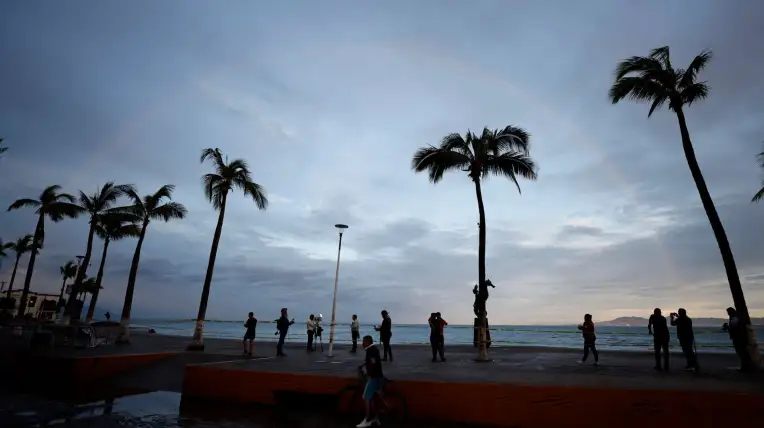 Personas frente a una playa en Puerto Vallarta tras el paso del huracán Simón.
