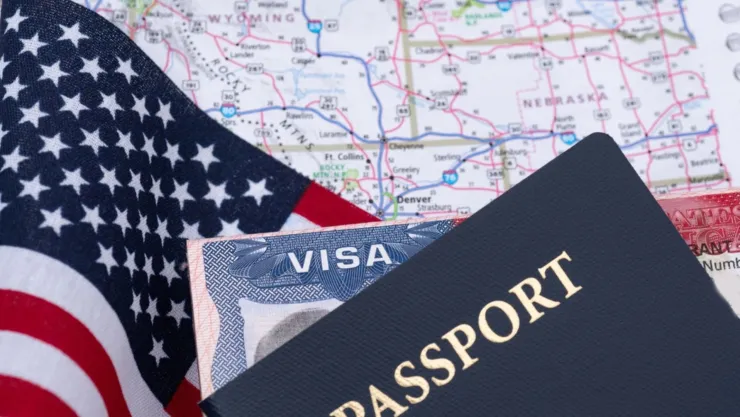 Un visado de Estados Unidos junto a una bandera y un mapa del país.