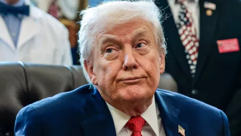 Donald Trump aparece sentado durante un evento oficial en la Casa Blanca, mientras responde preguntas de la prensa.