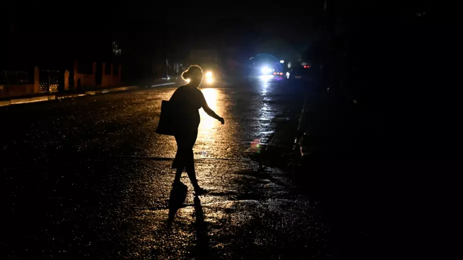 Una mujer camina por la calle durante un apagón mientras Cuba lucha por paliar los cortes de luz en medio de la reducción del suministro de combustible procedente de Venezuela, en La Habana, Cuba, 18 de noviembre de 2025.