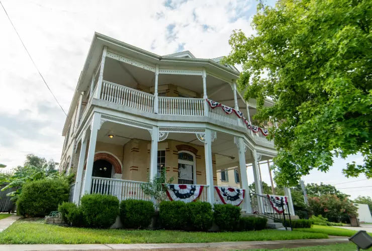 Una casa de dos plantas en un pueblo de Texas, con un parque verde de entrada prolijo y plantas en su alrededor