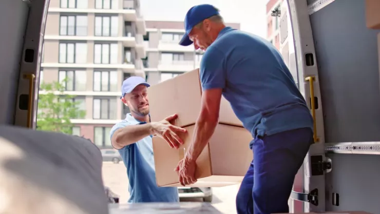 Dos hombres suben cajas a un vehículo de mudanza.