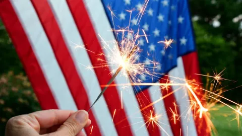 Una bengala prendida delante de una bandera estadounidense