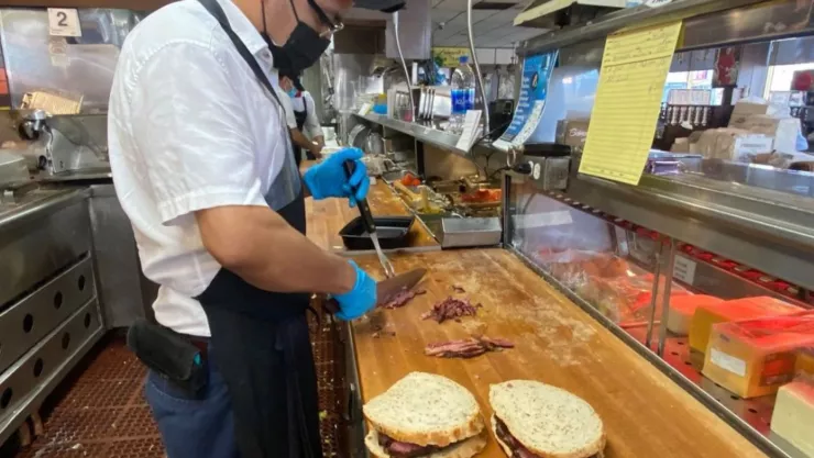 Un empleado de Langer’s Deli hace un sánduche de pastrami.