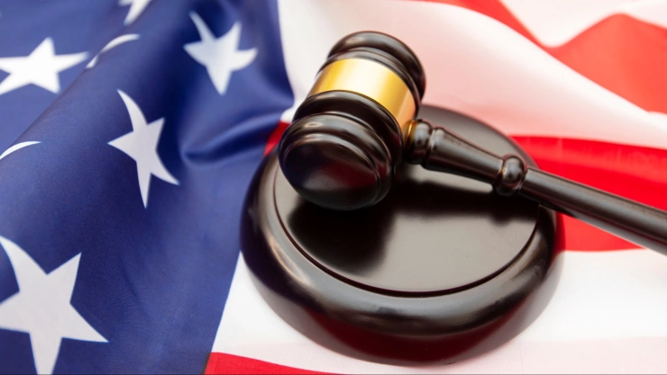 Postal de un bastón de juez y la bandera de Estados Unidos como fondo