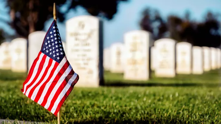 Una bandera de Estados Unidos cerca de unas lápidas en un cementerio.