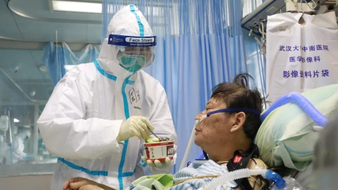 Nurse in a protective suit feeds a novel coronavirus patient inside an isolated ward at Zhongnan Hospital of Wuhan University