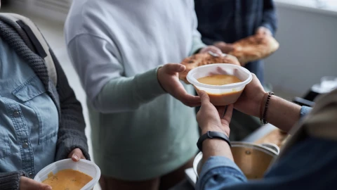 Una persona entrega un plato de comida a otros