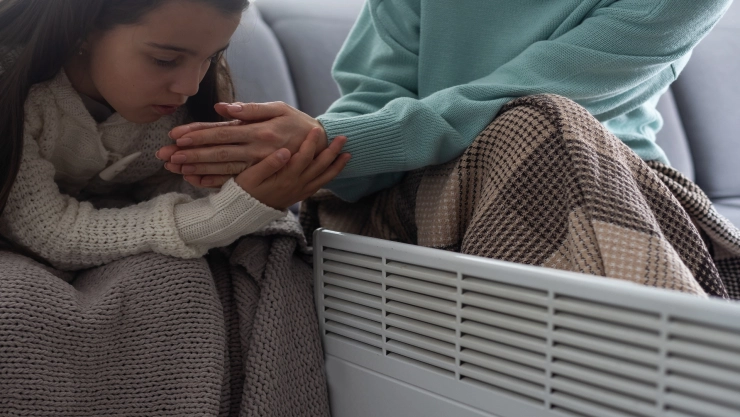 una ni&ntilde;a y su madre se refugian del fr&iacute;o con la calefacci&oacute;n