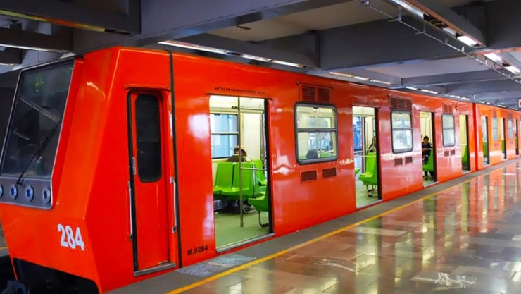 Un vagón naranja del Metro CDMX con los característicos asientos de color verde en su interior.