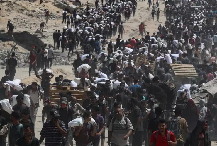 Decenas de personas cargan con costales de ayuda humanitaria en Gaza.