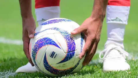 Jugador de la Liga MX agarrango el balón para tirar un penal