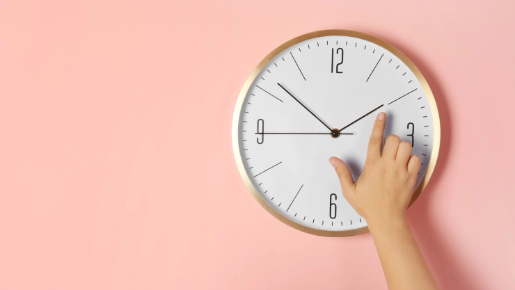 Mujer ajusta las manecillas de un reloj en la pared